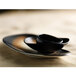 A close-up of a tiger organic porcelain plate with a black bowl on it.