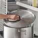 A person using a yellow glove to clean a Choice pot lid.