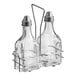 A set of two clear glass oil and vinegar cruet bottles with metal pour spouts, held in a metal wire rack.
