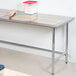 An Advance Tabco stainless steel open base work table with a rolling pin on it.