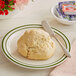 A plate with a biscuit and a knife with butter on it.