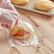 A person in plastic gloves putting a cookie in a printed plastic bag.