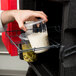 A hand using a Metro Mightylite Pan Carrier to hold a plastic container of food.