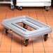 A Metro Mightylite Pan Carrier Dolly with metal wheels on a tile floor.