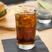 A Libbey highball glass filled with iced tea and a lemon slice on a table.