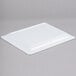 A white rectangular Elite Global Solutions melamine serving platter on a gray surface.