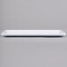 A white rectangular Elite Global Solutions melamine serving platter on a gray surface.