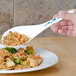 A hand using a Thunder Group Blue Bamboo rice ladle to serve rice over a plate of food.