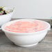 A clear plastic catering bowl lid on a table over a bowl of salad.