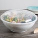 A Fineline clear plastic lid on a salad in a plastic bowl.