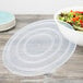 A clear plastic lid on a Fineline catering bowl filled with salad.