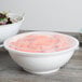 A white Fineline high profile plastic catering bowl filled with salad on a table.