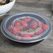 A Fineline black plastic catering bowl filled with strawberries.