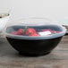 A close up of a Fineline black high profile plastic catering bowl filled with strawberries.