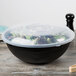 A Fineline black plastic catering bowl with a lid on top filled with salad.