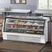 An Avantco white curved glass refrigerated deli case on a counter with meat and cheese inside.