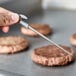 A metal needle on a metal rod touching a meat patty.