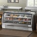 An Avantco stainless steel refrigerated deli case with curved glass displaying meat and cheese.