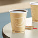 Two Solo Mistique paper hot cups filled with coffee on a table.