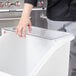 A person's hand reaching into a clear lid on a white container.