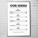 An Aarco aluminum slide frame holding a menu poster on a wall.