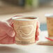 A hand holding a Solo Mistique paper hot cup of coffee with a lid.