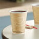 Two Solo Mistique paper hot cups of coffee on a table.