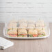 A clear Eco-Products Regalia compostable plastic lid on a tray of sandwiches with a napkin on the side.
