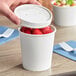 A white 16 oz. double poly-coated paper food cup with a vented paper lid, shown containing strawberries.