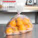 A group of oranges in a plastic bag.