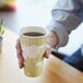 A hand holding an Eco-Products World Art insulated hot cup with a map on it.