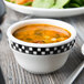 A bowl of soup on a wood table with a spoon.