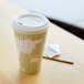 A white Eco-Products compostable plastic hot cup lid on a coffee cup with a world map design.