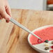 A hand using Mercer Culinary straight plating tongs to plate food.