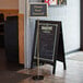 A Chef Master gold rectangular hostess sign on a stand.