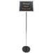 A long silver pole with a white sign on a black stand.