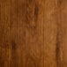 The wooden seat of a Lancaster Table & Seating Industrial Bar Stool with a dark stain.