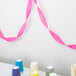 A hot magenta pink streamer on a table with colorful cups