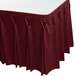 A burgundy Snap Drape table skirt with pleated bow tie pleats on a table.