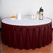 A table with a burgundy Snap Drape Wyndham table skirt on it.