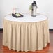 A cream shirred pleat table skirt with Velcro clips on a table with a tray of food and drinks.