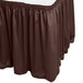 A brown table skirt with a white surface on a table.