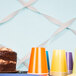 Shimmering silver streamer paper used as ribbon on a table with a cake and plastic cups.