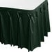 A jade green table skirt with bow tie pleats on a table with a black table cloth.