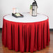 A table with a red Snap Drape table skirt and a tray of coffee cups.