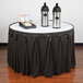 A table with a Snap Drape charcoal table skirt and two containers on it.