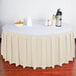 A table with a Snap Drape Bone Box Pleat Table Skirt on it with a black stripe.