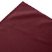 A burgundy box pleat table skirt with Velcro® clips on a white background.