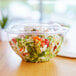 A salad in a clear plastic bowl with a lid.
