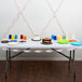 A table with a Classic Pink Streamer Paper table decoration, a cake, and plates on it.